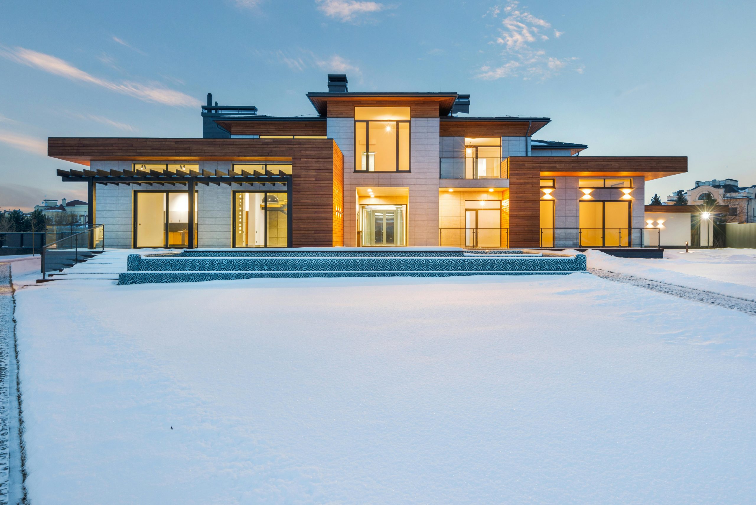 Exterior design of illuminated luxurious two storey villa with modern architecture and panoramic windows in wintertime